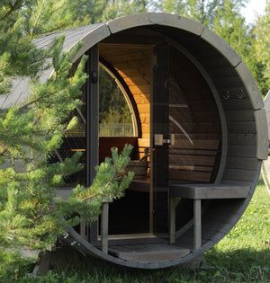 SaunaLife Outdoor Barrel Sauna with Glass Front - Positioned in a forest in the morning sun